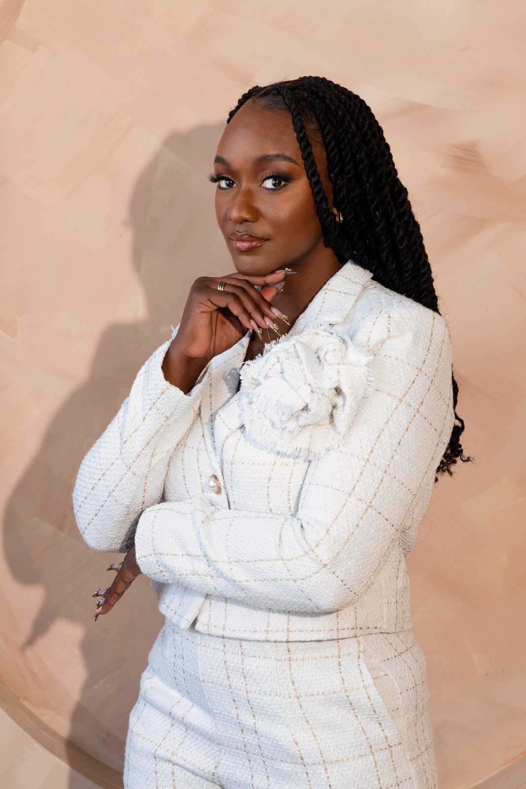 Attorney in a white tweed suit photographed against a warm painted backdrop